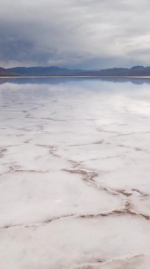 Dikey video. Badwater Havzası, Ölüm Vadisi Ulusal Parkı 'nda tuz tabakası oluşumlarının ayna yüzeyinde yürüyor. Kaliforniya, ABD