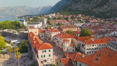 Karadağ 'ın Kotor kentindeki saat kulesiyle eski kentin üzerinde uçmak - Avrupa' nın popüler turizm beldesi. Kotor Körfezi - Boka - ve arka planda dağlar. Hava atışı, 4K