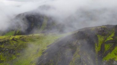 Kötü bulutlu havada dağlarda tehlikeli bir uçuş. Düşük bulutlu, yağmur ve rüzgarlı dağlardaki uçak uçuşlarının havadan görüntüsü. Güvenli olmayan uçuş