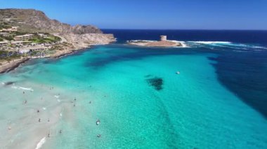 İtalya 'nın Sardunya adasındaki ünlü La Pelosa plajının hava görüntüsü. Turistler La Pelosa plajında turkuaz suyla denizde yüzerler.