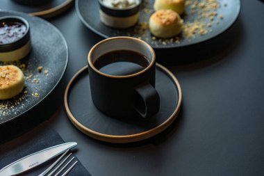 Ekşi kremalı ve reçelli siyah tabakta süzme peynirli kek.