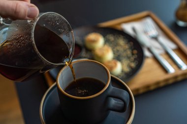 Ekşi kremalı ve reçelli siyah tabakta süzme peynirli kek.