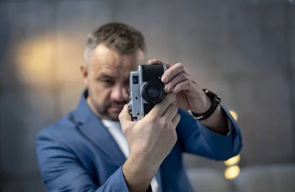 スーツを着た髭の男がヴィンテージのフィルムカメラを持っている 灰色の背景で撮影した高品質の写真 — ストック写真