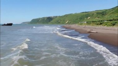 Okhotsk Denizi 'nin köpüklü dalgaları üzerinde uçarken Sakhalin Adası yakınlarındaki kumlu bir plaja doğru koşuyor. Yüksek kaliteli FullHD görüntüler