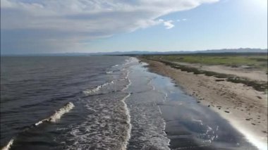 Okhotsk Denizi 'nin köpüklü dalgaları üzerinde uçarken Sakhalin Adası yakınlarındaki kumlu bir plaja doğru koşuyor. Yüksek kaliteli FullHD görüntüler