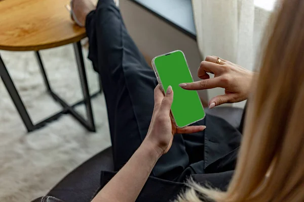 stock image a womans hand holds a modern smartphone on a green street background.close up.green screen for your design.copy-space. High quality photo