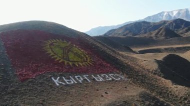 Kırgızistan bayrağı dağda bulunmaktadır. Yere bir bayrak çizmek. Yüksek kalite 4k görüntü