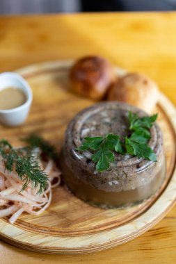 Damalı peçete, bir parça et jölesi, fesleğen, beyaz cam tabakta sarımsak dilimleri, mutfak bıçağı ve ahşap masa çatalı. Yüksek kalite fotoğraf