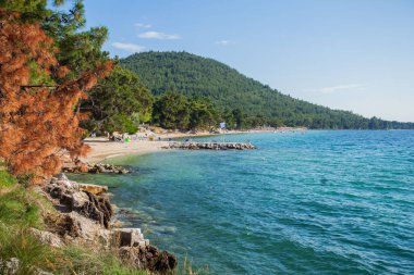 Doğal güzelliğin muhteşem panoramik manzarası turkuaz berrak deniz suyu, çakıl taşı plajı, yaz günü sahilde turistler.. 