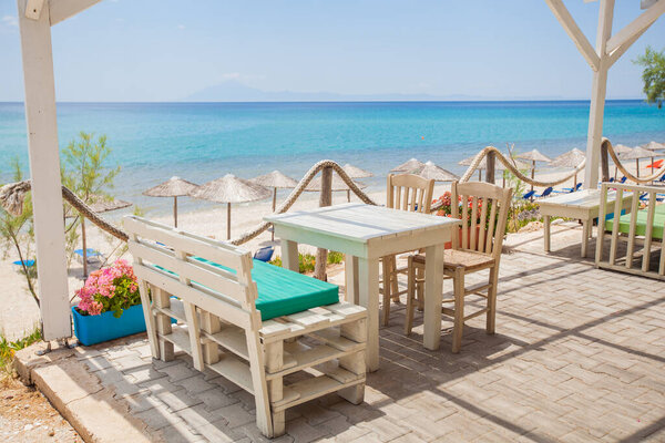 Waterfront Restaurant. Beachfront View. Summer Seascape. Picture-perfect Postcard Moment. Feast For Eyes. Overlooking the Aegean Twinkling Blue Waves.