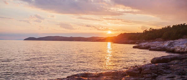 海の地平線の上にロマンチックな夏の日没や日の出の風景 水面に太陽光の反射 岩の多いビーチでの黄金の時間ライト — ストック写真
