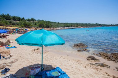 Arka planda mavi gökyüzü ve şemsiyeli kumsal. Yaz tatili.
