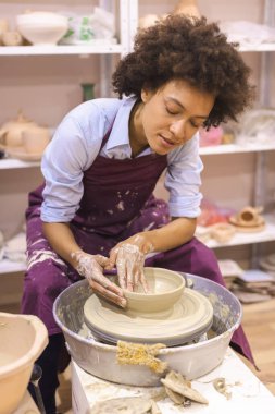 Çömlek çarkında kil şekillendiren yaratıcı Afro-Amerikan genç kadın. Seramik stüdyosunda atölye çalışması. Kadın sanatçı.. 