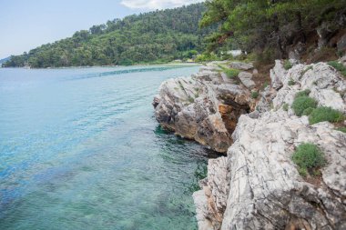  Deniz ufku ve mavi gökyüzü olan kayalık kıyı şeridiyle çevrili gizli bir sahil. Yalnızlık ve güzellik. Kayalar ve kıyı şeridi gizli ve romantik bir kaçış için güzel gökyüzü ve deniz dalgalarıyla buluşur..