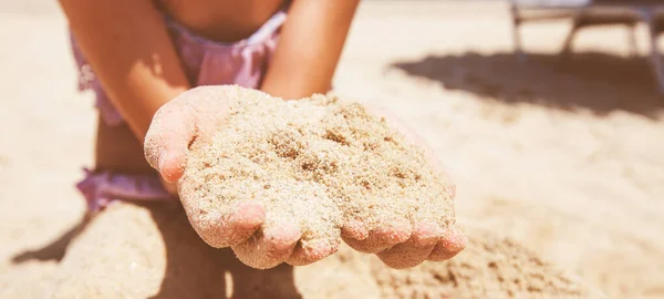 ビーチで砂を保持する小さな女の子の手のクローズアップ — ストック写真