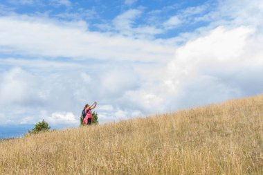 Güzel yaz manzarasının fotoğrafını çeken yürüyüşçü bir kadın..
