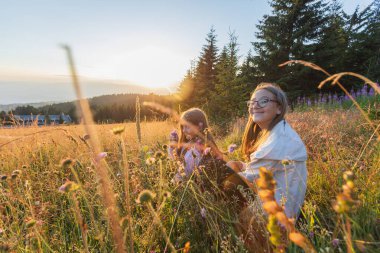 Gülümseyen çocuklar gün batımında çiçek çayırlarında eğleniyorlar..