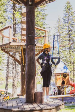 Bir yaz kampı sırasında, gür bir ormanın göbeğindeki heyecan verici ağaç tepesi macera parkında korkusuz genç kız..