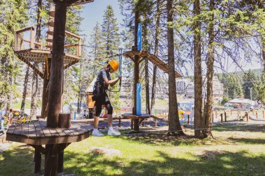Bir yaz kampı sırasında, gür bir ormanın göbeğindeki heyecan verici ağaç tepesi macera parkında korkusuz genç kız..