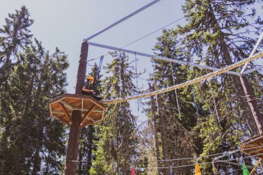 Bir yaz kampı sırasında, gür bir ormanın göbeğindeki heyecan verici ağaç tepesi macera parkında korkusuz genç kız..
