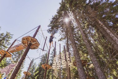 Bir yaz kampı sırasında, gür bir ormanın göbeğindeki heyecan verici ağaç tepesi macera parkında korkusuz genç kız..