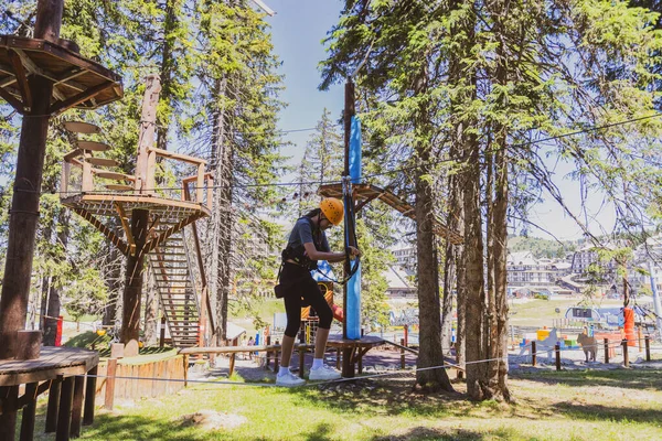 Bir yaz kampı sırasında, gür bir ormanın göbeğindeki heyecan verici ağaç tepesi macera parkında korkusuz genç kız..