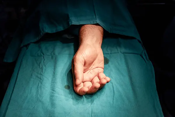 無菌手術室で手術できる手術テーブルの患者さんの手 ストック画像