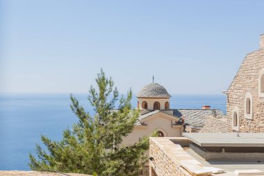 Yunanistan 'ın Thassos kentindeki büyüleyici Ortodoks kilisesi, beyaz cepheli, gri taştan çatılı, açık mavi gökyüzü altında. Kültürel ve mimari temalar için mükemmel, Başmelek Michael Manastırı.
