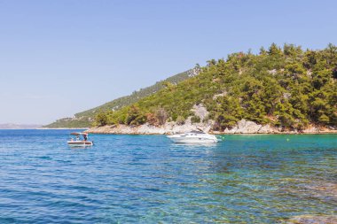 Akdeniz 'in sakin sularına bakan güneşli kayalık plajlarda yüzen tekneler var..