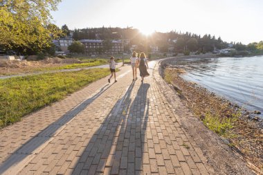 Bir aile Doiran Gölü 'nün huzurlu kıyı şeridi boyunca yürür, ılık günbatımı ışığında yıkanır..