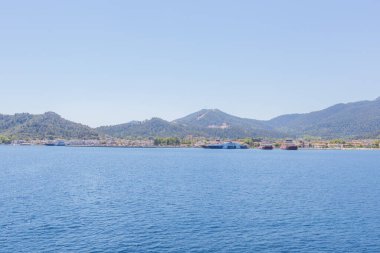 Yunanistan 'ın Thasos Adası' ndaki feribot limanı, feribotlar kenetlendi ve arka planda manzaralı dağ manzarası var.