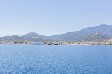 Yunanistan 'ın Thasos Adası' ndaki feribot limanı, feribotlar kenetlendi ve arka planda manzaralı dağ manzarası var.