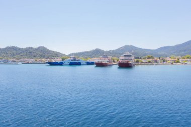 Yunanistan 'ın Thasos Adası' ndaki feribot limanı, feribotlar kenetlendi ve arka planda manzaralı dağ manzarası var.