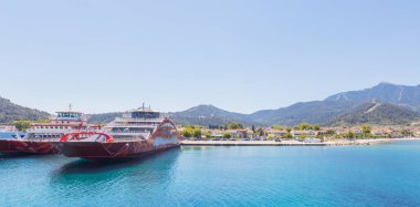 Yunanistan 'ın Thasos Adası' ndaki feribot limanı, feribotlar kenetlendi ve arka planda manzaralı dağ manzarası var.