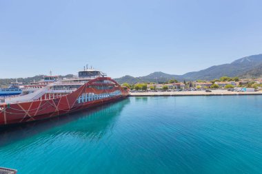 Yunanistan 'ın Thasos Adası' ndaki feribot limanı, feribotlar kenetlendi ve arka planda manzaralı dağ manzarası var.