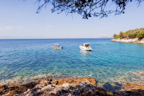 Akdeniz 'in sakin sularına bakan güneşli kayalık plajlarda yüzen tekneler var..