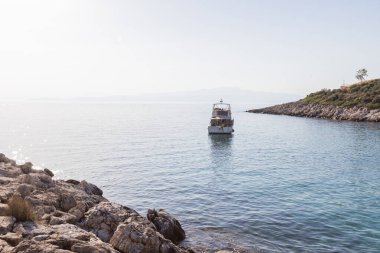 Yunanistan 'da manzaralı bir körfezde kayalık bir kıyıya yanaşmış pitoresk bir tekne. Sakin yaz ortamı.