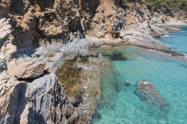 Yunanistan 'da kristal berraklığında suları olan kayalık bir sahil. Engebeli kıyı şeridi sakin ve şeffaf denizle güzel bir tezat oluşturuyor. Rahatlamak için ideal bir yer sunuyor..