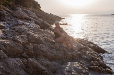 Huzurlu bir yaz tatilinin tadını çıkaran kadın, Deniz kenarında gün batımında Rocky Sahili 'nde dinleniyor.