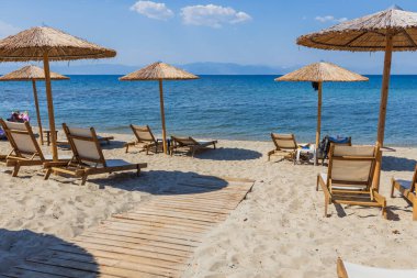 Saman Şemsiyeler ve Kumsalda güneşli yataklar Sakin mavi deniz manzaralı