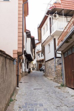 Makedonya 'nın kuzeyindeki tarihi Ohri kasabasından geçen dar bir kaldırım taşı sokağının manzarası. Büyüleyici taş evler, renkli yüzler ve geleneksel mimari..