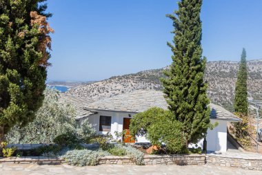 Thassos Adası 'nın manzaralı denizi ve engebeli dağlarını gören yemyeşil ve selvi ağaçlarıyla çevrili taştan çatılı geleneksel Yunan evi..