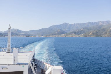 Feribot Mavi Deniz 'in Ötesinde, Arkaplanda Dağ Manzarası ile Kalkıyor