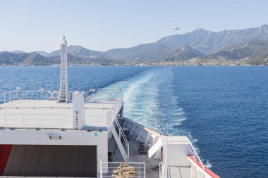 Feribot Mavi Deniz 'in Ötesinde, Arkaplanda Dağ Manzarası ile Kalkıyor