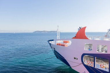 Feribot pruvası, berrak bir gökyüzü altında uzak Yunan adalarıyla sakin mavi sulara doğru yol alıyor..