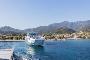 Feribot Dağlık Manzarası ve Açık Mavi Suları olan Sahil Kasabasına yaklaşıyor.