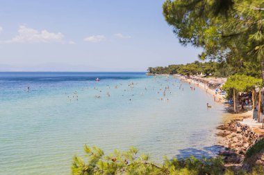 Yunanistan 'da turkuaz suları, kayalık kıyı şeridi ve arka planda yeşil tepeleri olan sakin bir sahil koyuna..