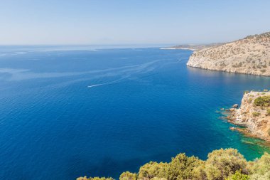 Berrak gökyüzünün altındaki engebeli mavi deniz ve kayalık uçurumların çarpıcı manzarası..