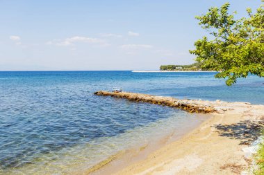 Denizin sakin, mavi sularına uzanan bir taş iskelenin sakin manzarası, yaz tatili..