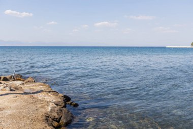 Denizin sakin, mavi sularına uzanan bir taş iskelenin sakin manzarası, yaz tatili..